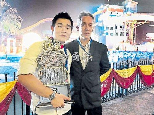 中國僑網擁抱著2017年第3屆奧林匹克國際青年廚師大賽亞軍獎杯的歐開賓（左），與大會評判合影。（馬來西亞《中國報》）