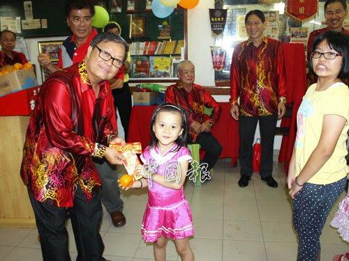 中国侨网黄振福（左）分派红包给出席的小孩。（马来西亚《中国报》）